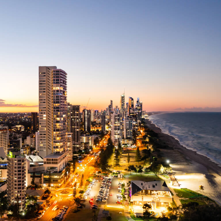 Areal shot of Broadbeach lit up with night lights at sun set.