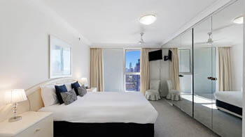 Bright bedroom with city views and mirrored built-in wardrobes at ULTIQA Beach Haven on Broadbeach.