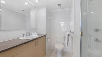 Spacious bathroom with toilet, shower and large mirrored vanity at ULTIQA Beach Haven on Broadbeach.