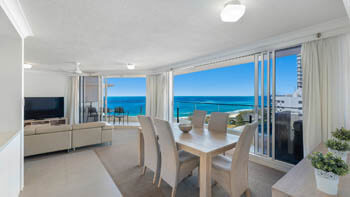 Spacious dining and living area with white curtains and stunning views of the ocean at ULTIQA Beach Haven on Broadbeach.