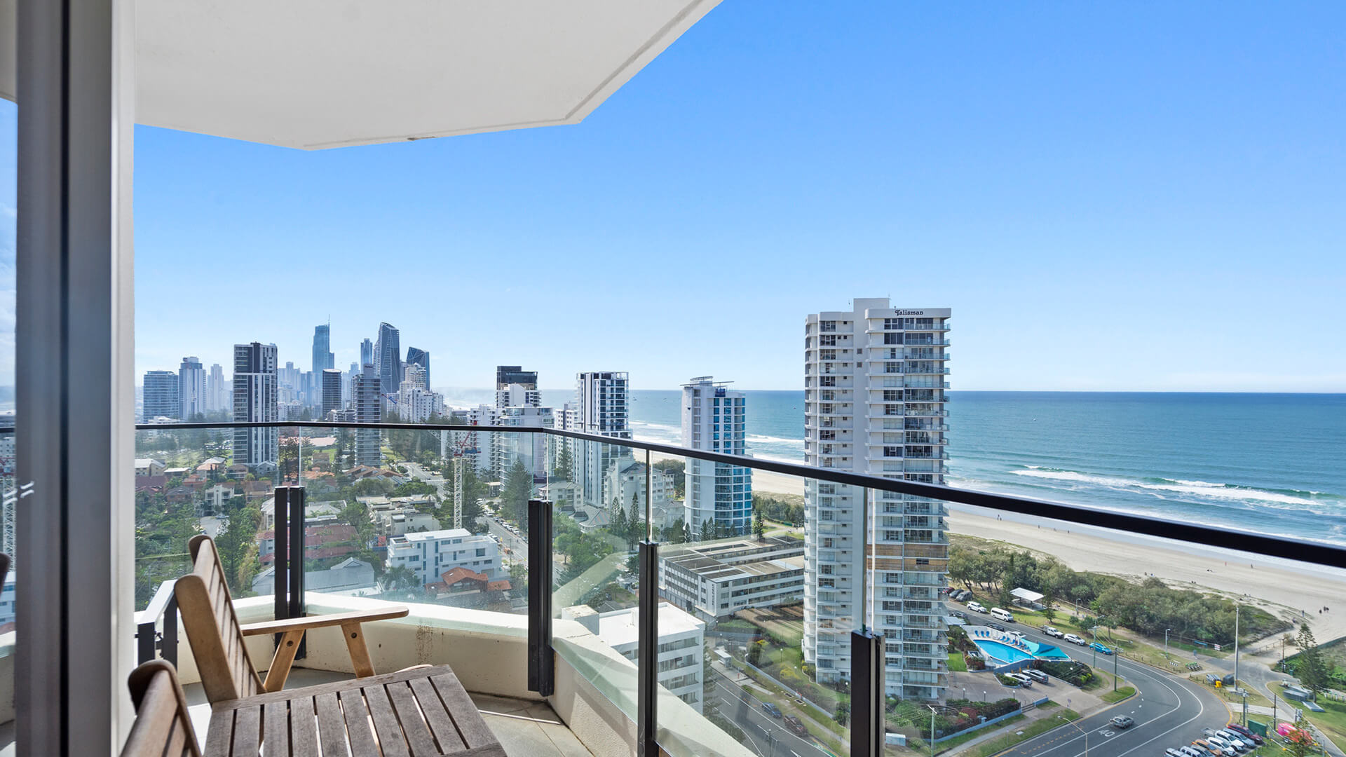 View of Broadbeach from the balcony at ULTIQA Beach Haven on Broadbeach with a nice wooden outside furniture set of a table and two chairs.