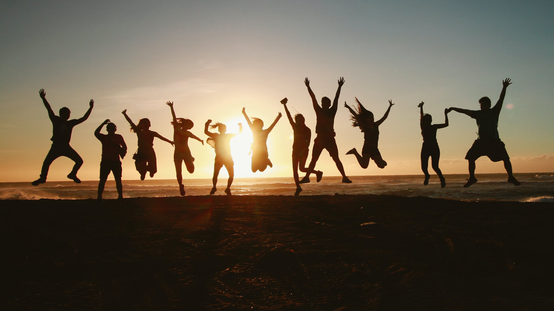 People Jumping on the beach at sunset