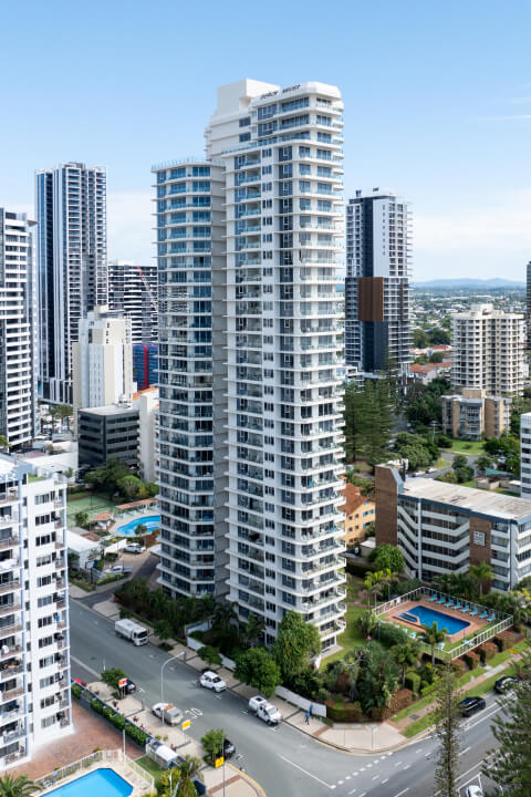 Outdoor pool area at ULTIQA Points North featuring sun loungers, tropical palm trees, and views of the resort's high-rise building.