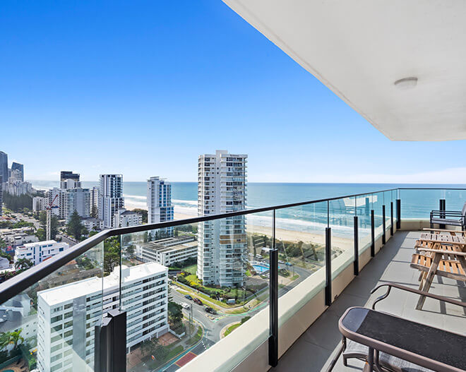 Scenic oceanfront boardwalk in Coolangatta with turquoise water, golden sand, and high-rise buildings along the coastline under a bright blue sky.