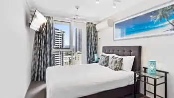 Second bedroom with a king bed and a TV in the corner at ULTIQA Beach Haven on Broadbeach.