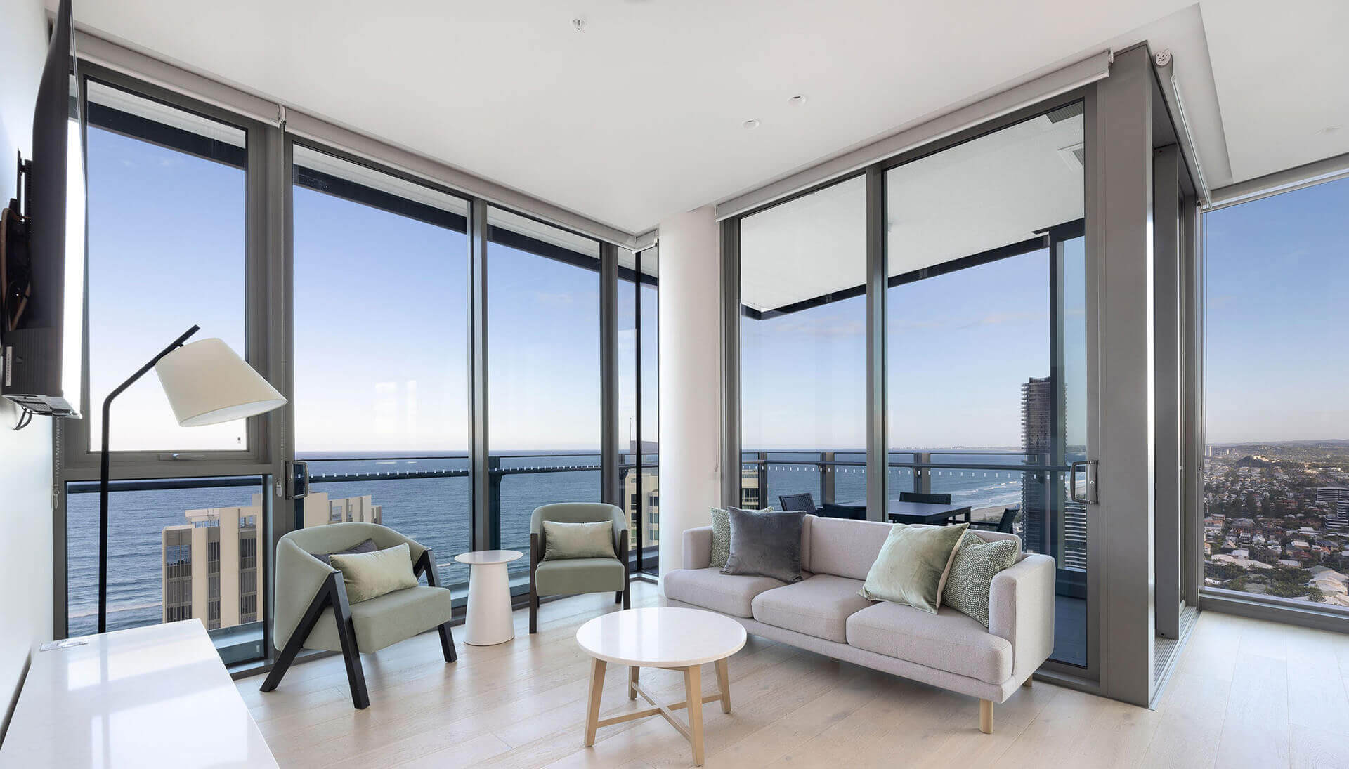 Modern living room at ULTIQA Signature at Broadbeach with floor-to-ceiling windows, ocean views, and contemporary furnishings.